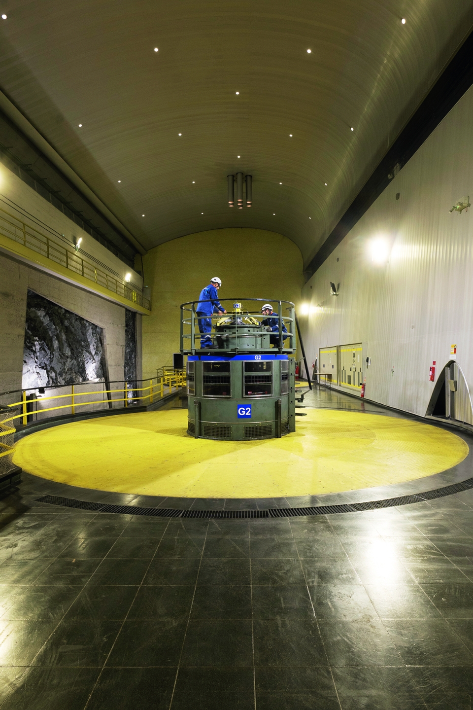 Le principe d’une centrale hydroélectrique est d’utiliser la force de l’eau pour entraîner une turbine qui va produire de l’électricité. Ici, on peut voir la tête d’une turbine. Le sol jaune et noir, tout comme le toit éclairé façon ciel étoilé, montre le souci du décorum des architectes à l’époque. Cette salle est aujourd’hui classée. Rien n’a changé depuis les années 60.