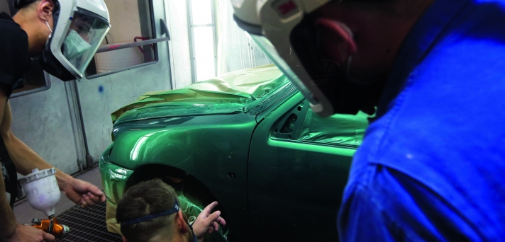 Jeunes en formations en mécanique sur une voiture.